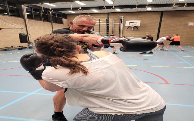 Trainer oefent boksbewegingen met een lid
