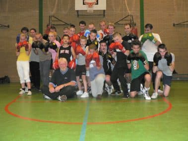 Oudere groepsfoto van leden met bokshandschoenen in de gymzaal