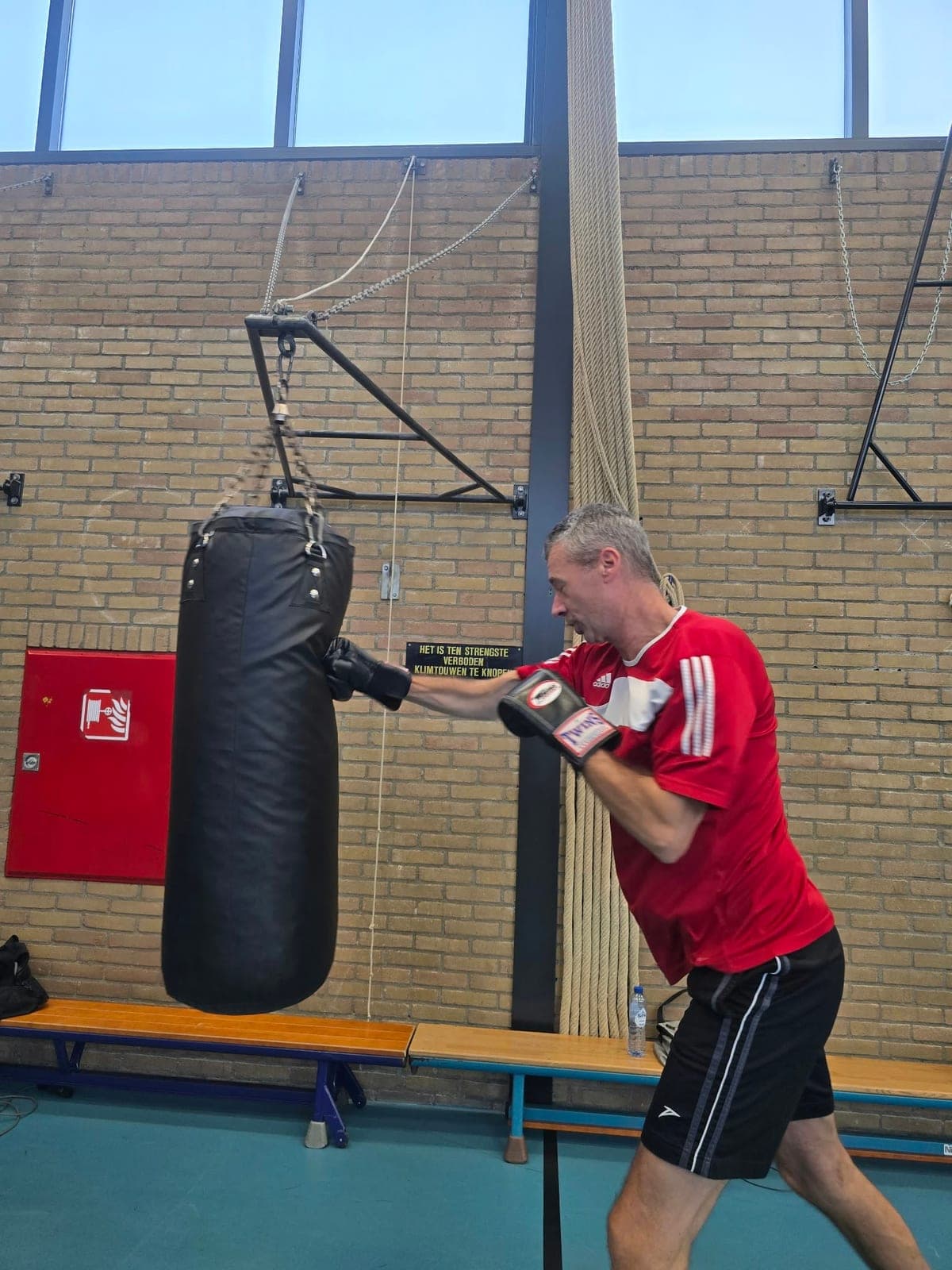 Trainer Mike stoot op de bokszak in de gymzaal